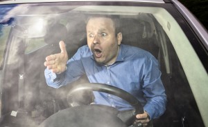 Sprawdź, jakim kierowcą jesteś psychotest, czyli zdenerwowany mężczyzna w niebieskiej koszuli za kierownicą samochodu